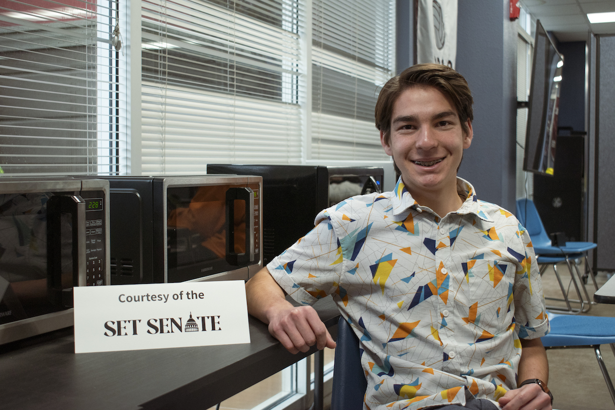 A 12th grade student at the School for Entrepreneurship and Technology (SET High), a tuition-free charter high school in San Diego, poses in front of  microwaves in the cafeteria as part of a student-led initiative. 
