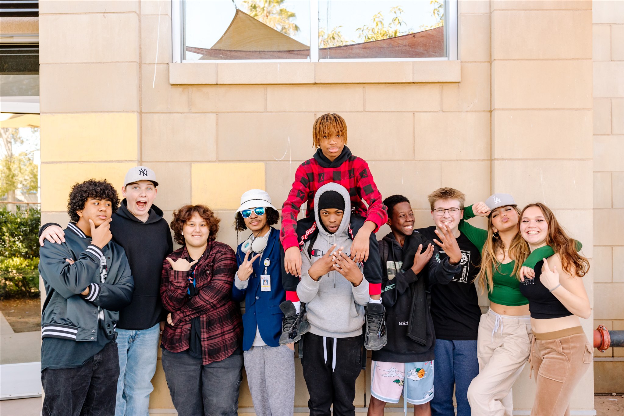 A group of SET High students stands in a line outside of the high school building facing and posing for the camera.