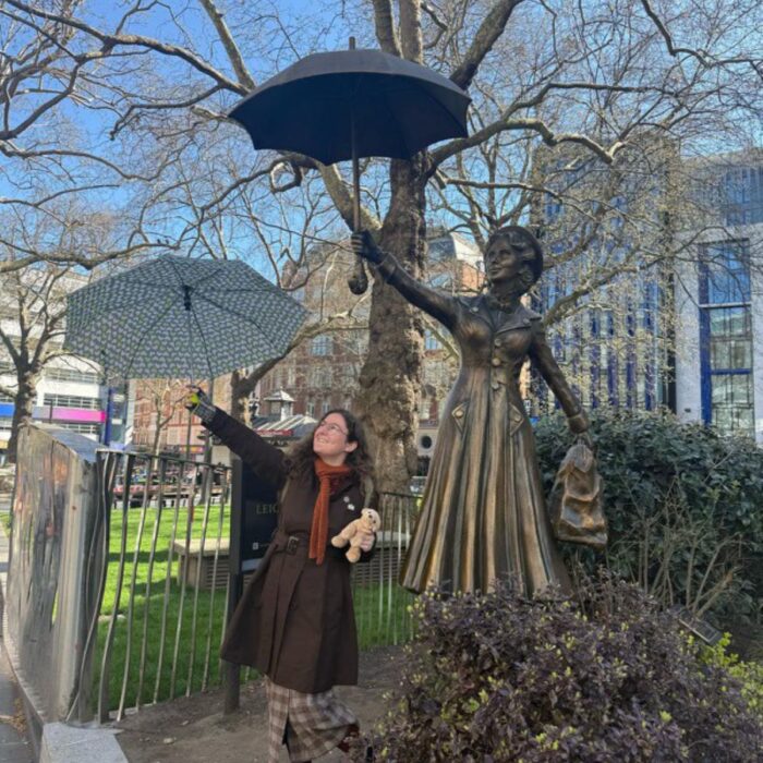 SET High graduate Althea Chialtas mimics a statue of Mary Poppins behind her and holds an umbrella high up in their right hand and left leg slightly raised while smiling.