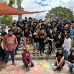 A group of SET High students, mostly in black t-shirts with “SET” written on them, stand on concrete steps outside the school.